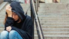 Person sitting on steps with their head in their hands