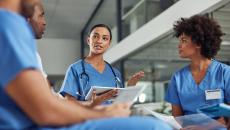 Three healthcare providers sitting in a circle and talking to each other