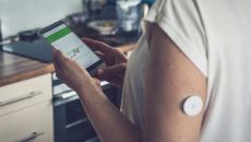  A patient with a wearable sensor patch checking their blood glucose level through a mobile app