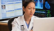 Healthcare professional sitting at a desk with many computers around them