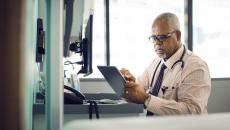 Healthcare provider sitting at a desk while looking at a tablet
