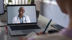 Physician interacting remotely with a person via laptop