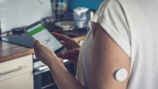 Image of person with glucose patch looking at a smartphone