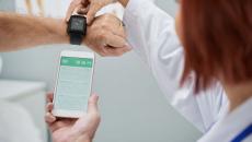 Doctor showing patient how to synchronize health app in smartphone and smartwatch