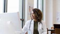 Healthcare provider sitting at a desk while looking at a computer 