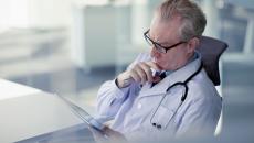 Healthcare provider looking at a tablet while holding their chin as though deep in thought