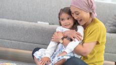 Two people sitting on the floor next to a couch with one wearing a head scarf