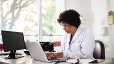 Healthcare provider sitting in an office at a desk with a computer on it