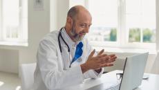 Healthcare provider sitting at a desk while looking at a laptop