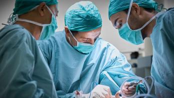 Three surgeons operating on a patient