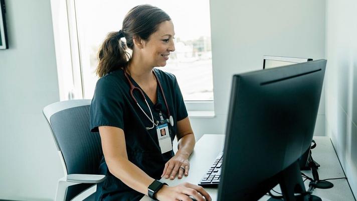 A doctor reviewing a patient's record on a desktop computer
