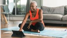 A woman takes an online exercise class on a tablet
